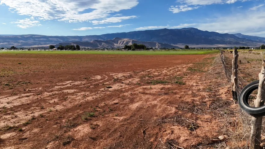 Expansive open land with distant mountain backdrop and established fencing