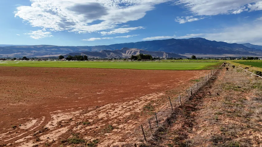 Expansive land parcel featuring open fields, distant mountains, and a perimeter fence