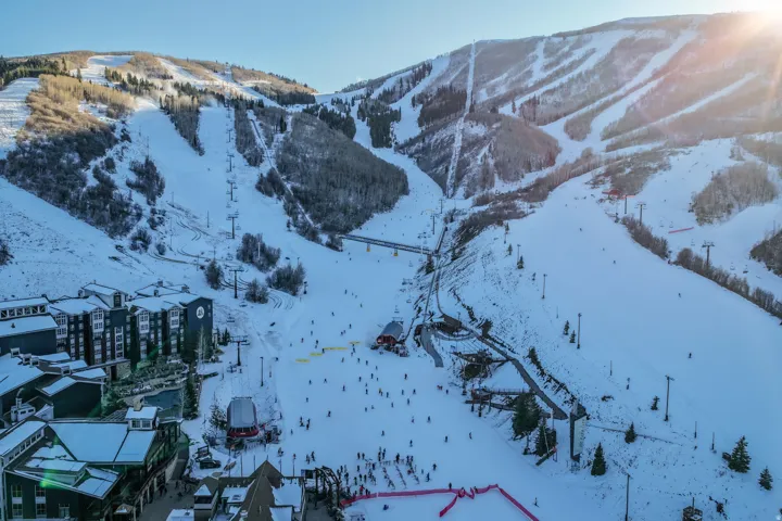 Snow-covered mountain slope featuring multiple ski runs and chairlifts, surrounded by dense evergreen trees