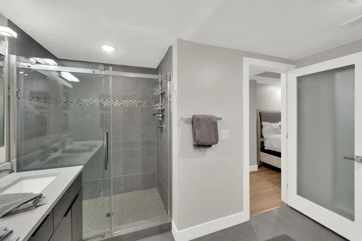 Shower enclosure with sliding glass door, mosaic tile accent, and hexagonal tile floor