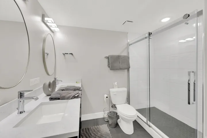Dual vanity with integrated sinks, chrome fixtures, and a spacious glass-enclosed shower with subway tile surround
