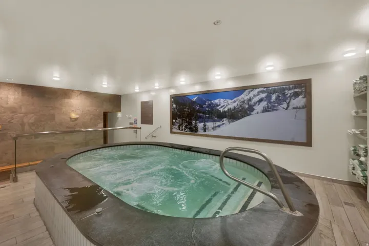 Indoor pool with integrated steps and handrails, stone accent wall, recessed lighting, and wood-finish flooring