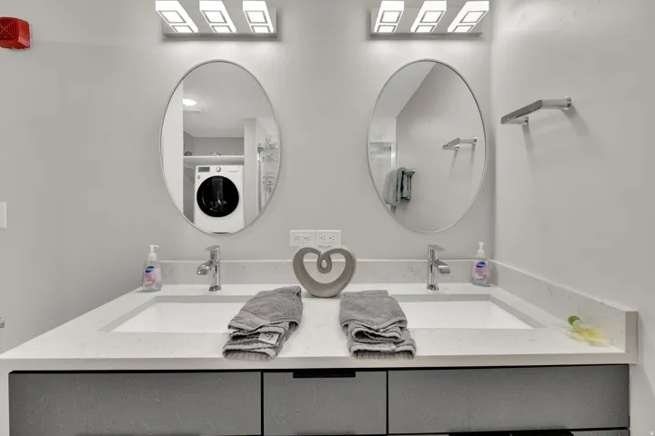 Dual vanity with integrated sinks, light-toned countertop, and contemporary rectangular light fixtures