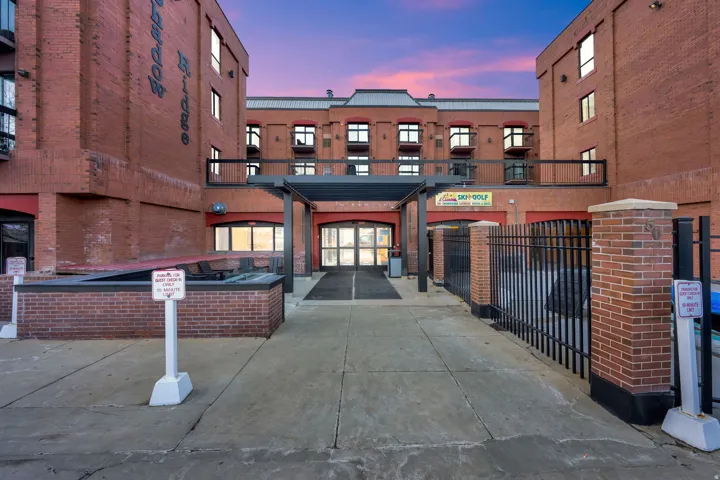 Brick exterior with multiple windows, concrete walkway, and a covered entrance