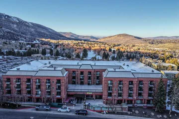 Brick exterior with multiple balconies, a snow-dusted roof, and surrounding mountainous terrain