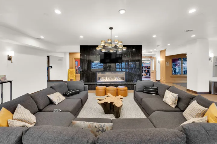 Recessed lighting illuminates a modern fireplace with a dark stone surround