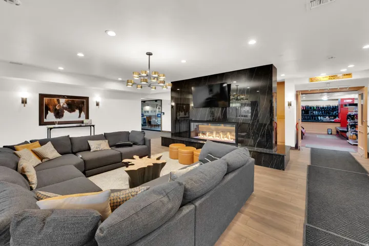 Modern electric fireplace with a black stone surround, recessed lighting, and wood-finish flooring