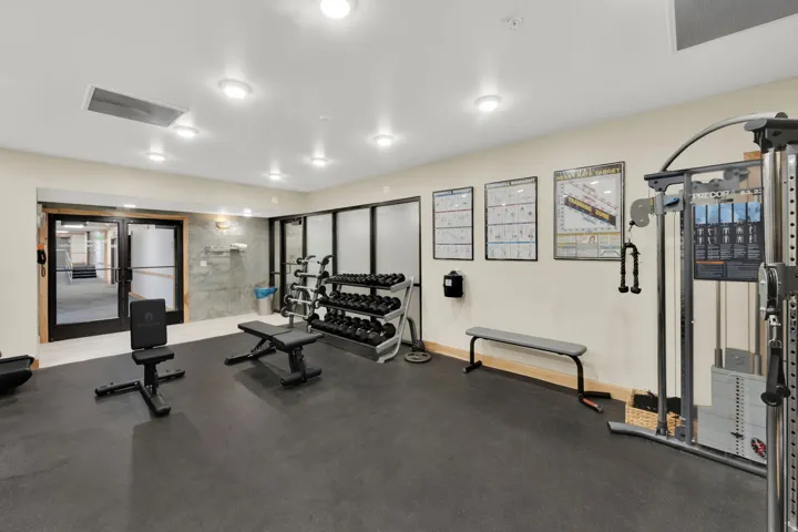 Dedicated fitness area featuring rubber flooring, built-in recessed lighting, and a neutral wall palette