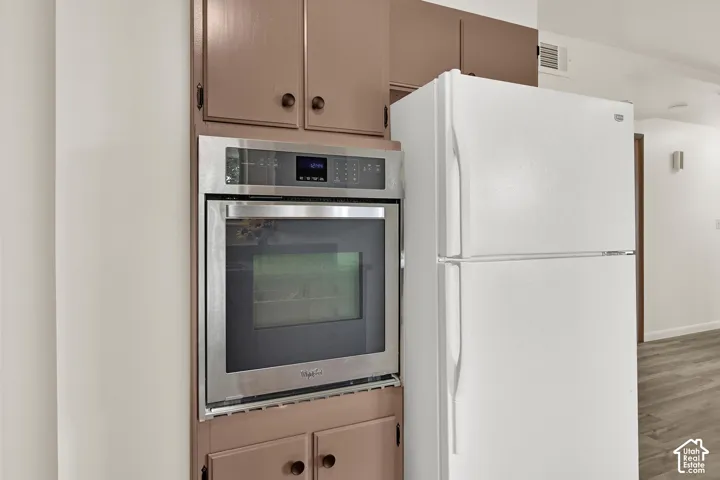 Built-in stainless steel oven with an integrated control panel, accompanied by a white refrigerator, New Flooring