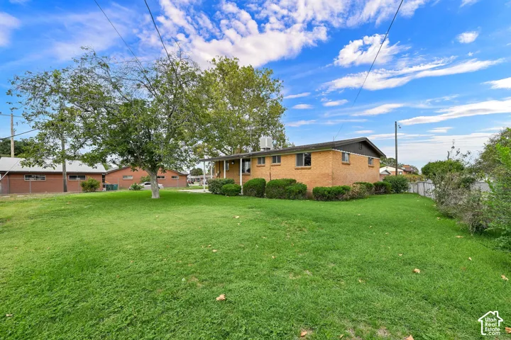 Expansive lawn with mature trees, brick exterior, and a covered front entry with white railings
