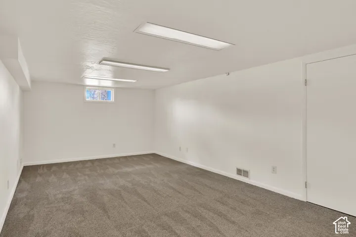 Spacious room featuring New neutral carpet, white painted walls, and recessed lighting