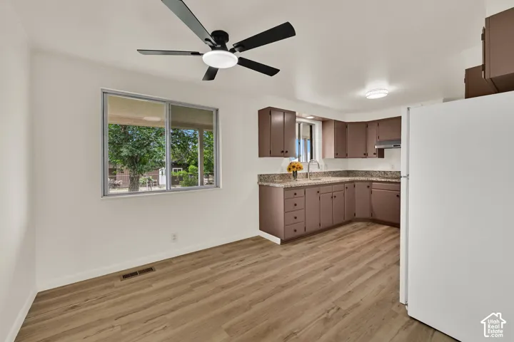 New Wood-finish flooring, New ceiling fan with integrated lighting, Fresh paint white walls, and a U-shaped kitchen with brown cabinetry and light-colored countertops