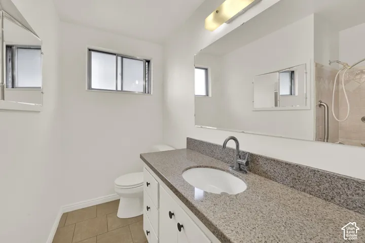 Main Bathroom featuring a spacious vanity with an integrated sink, stone countertop, white cabinetry with dark hardware, and a large wall-mounted mirror