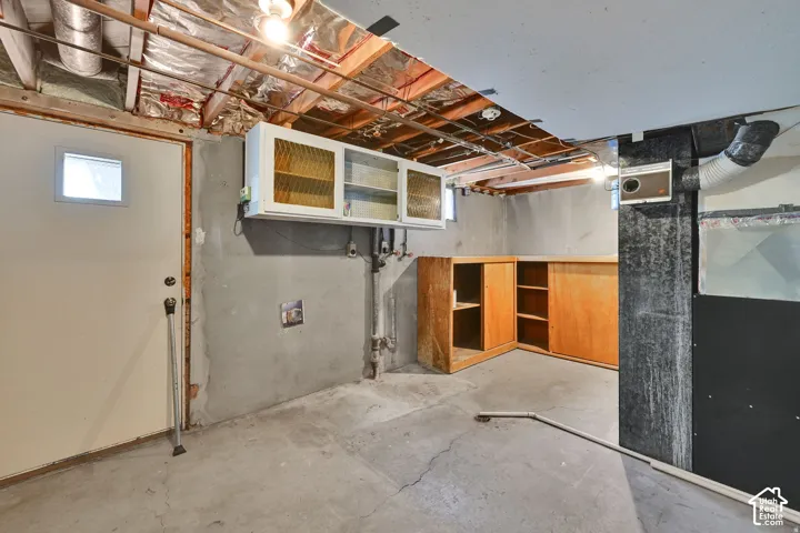 Back Basement Door. Concrete flooring with exposed ceiling joists and utilities