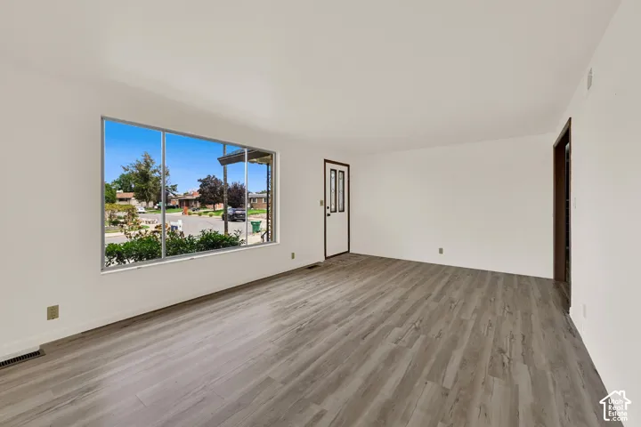 Expansive living area featuring New LVP wood-finish flooring, Fresh painted  white walls, and a large picture window
