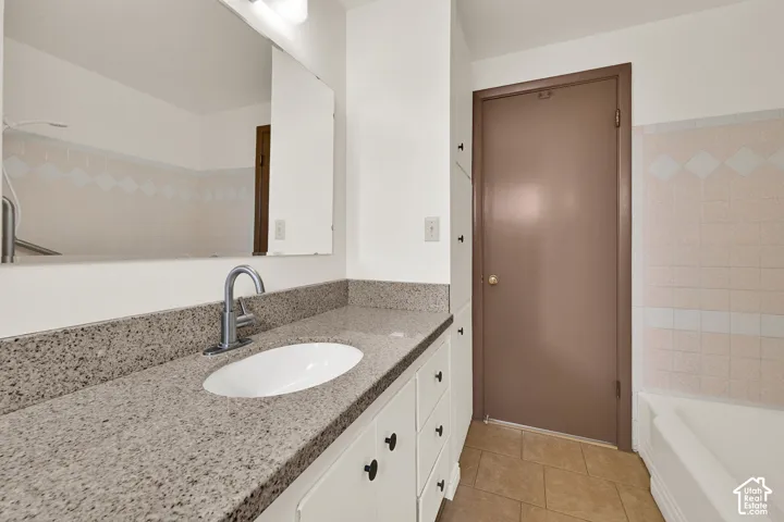 Main bathroom Vanity with stone countertop, undermount sink, and chrome faucet