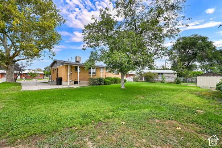 Expansive grassy yard with mature trees and a detached shed