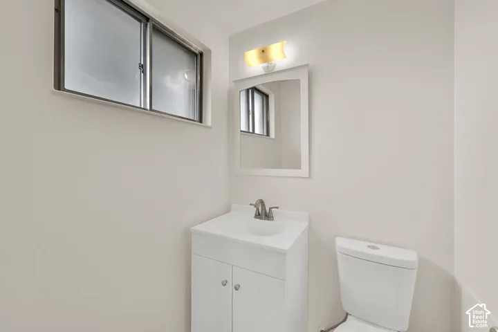 Recessed window with frosted glass, white vanity with integrated sink, chrome faucet, wall-mounted mirror, and overhead vanity lighting. Primary bath.