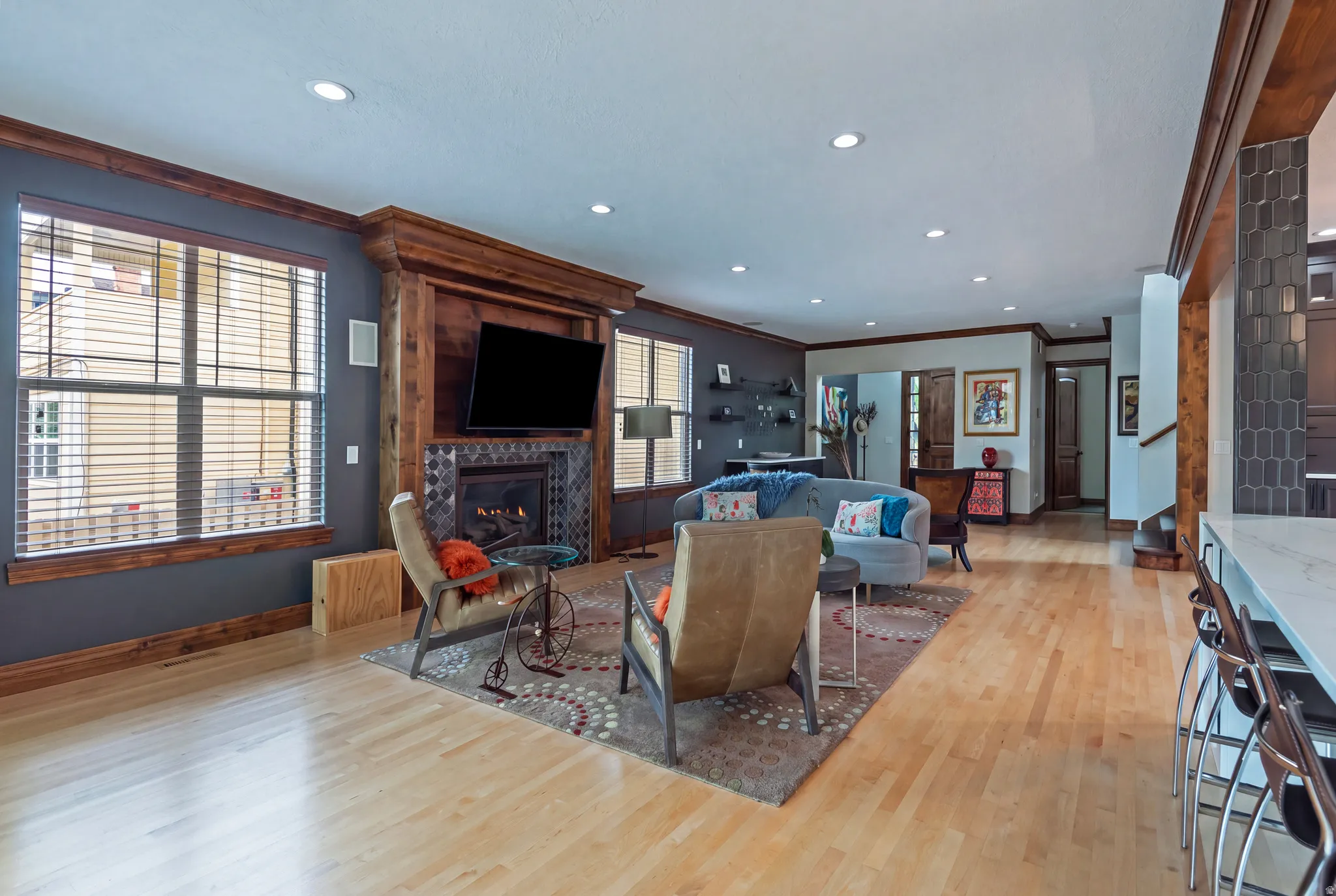 Wood-finish flooring, recessed lighting, and a fireplace with decorative tile surround