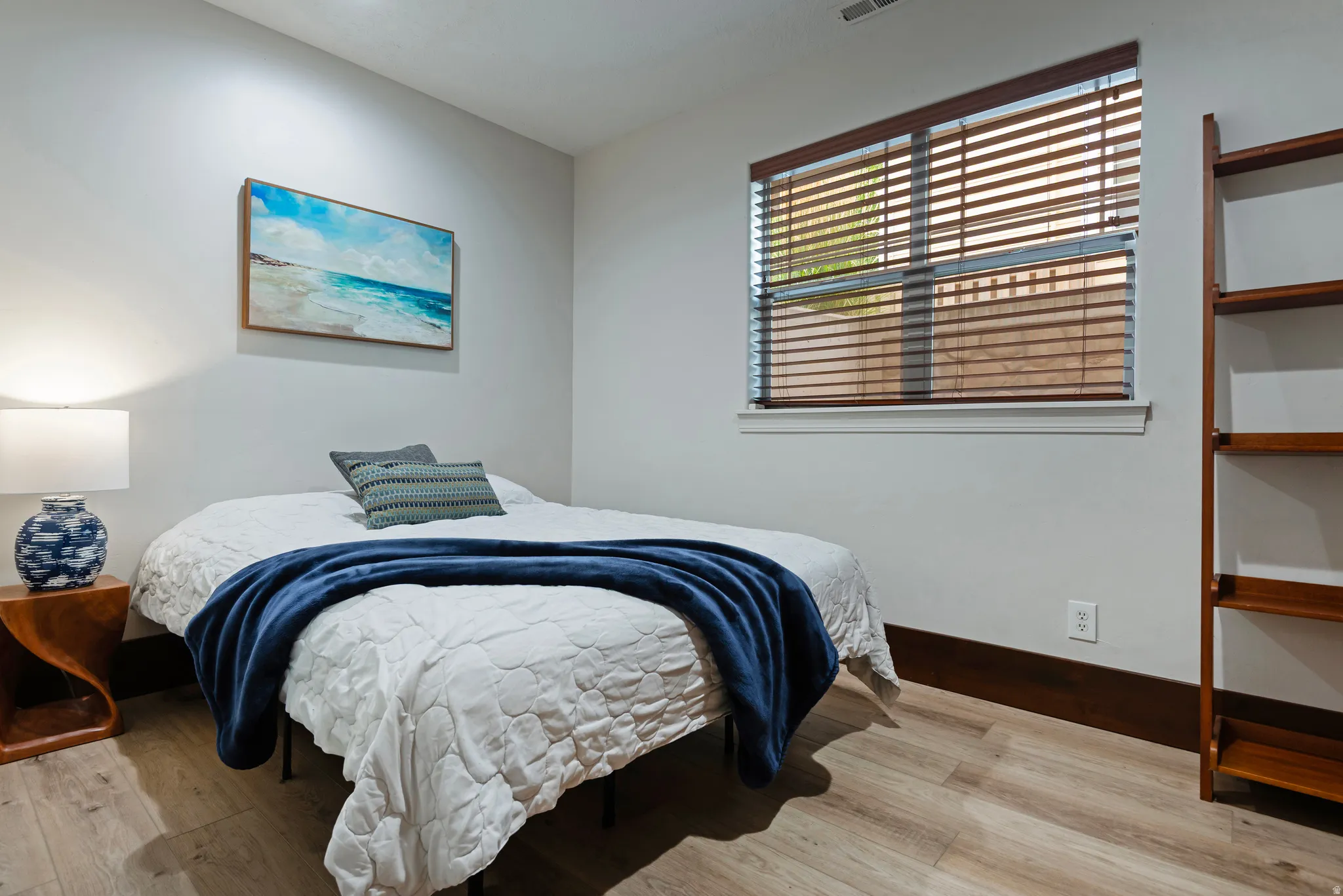 Wood-finish flooring, white walls, and a window with wood blinds