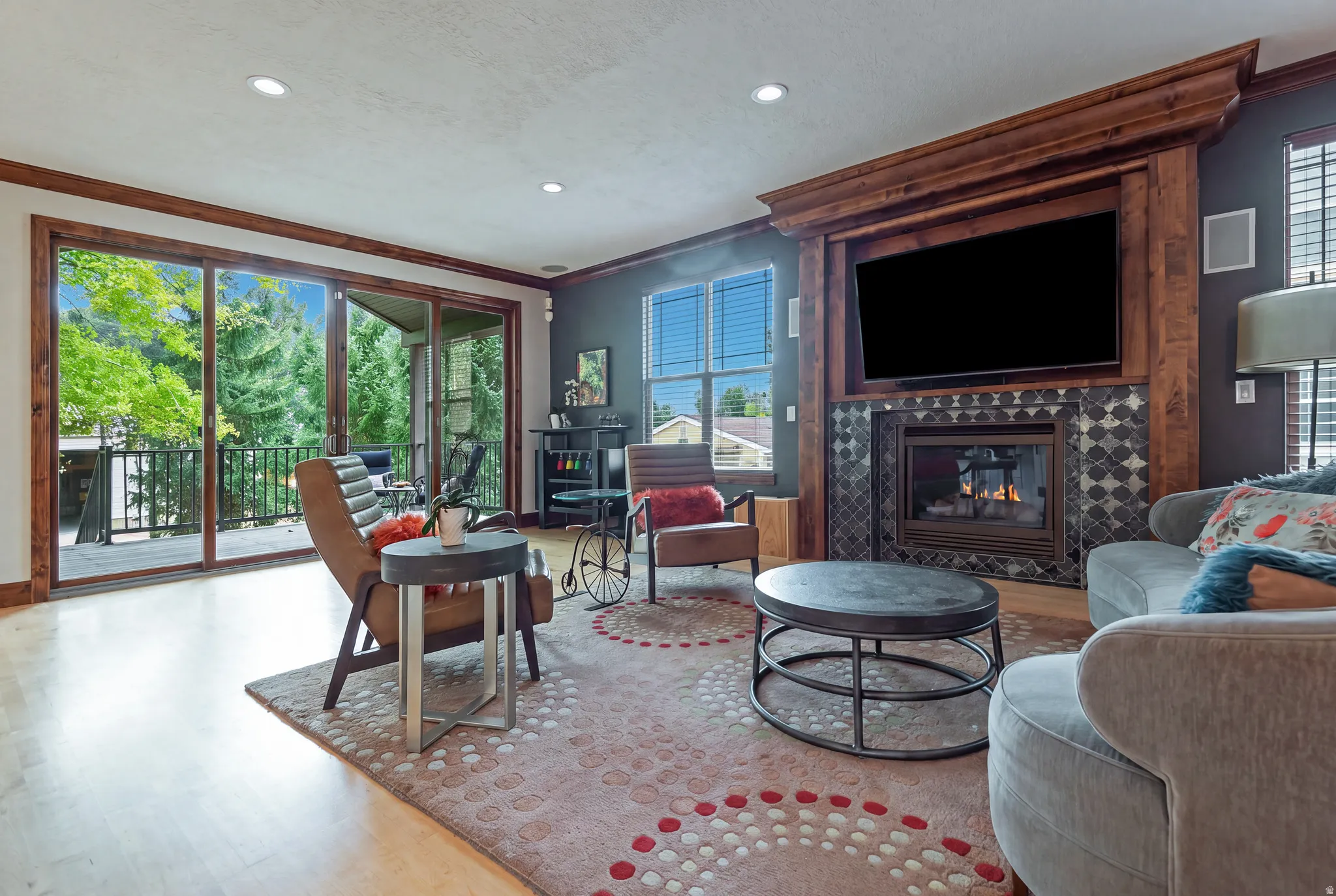 Wood-finish flooring, recessed lighting, and a fireplace with a decorative tile surround and wood mantel