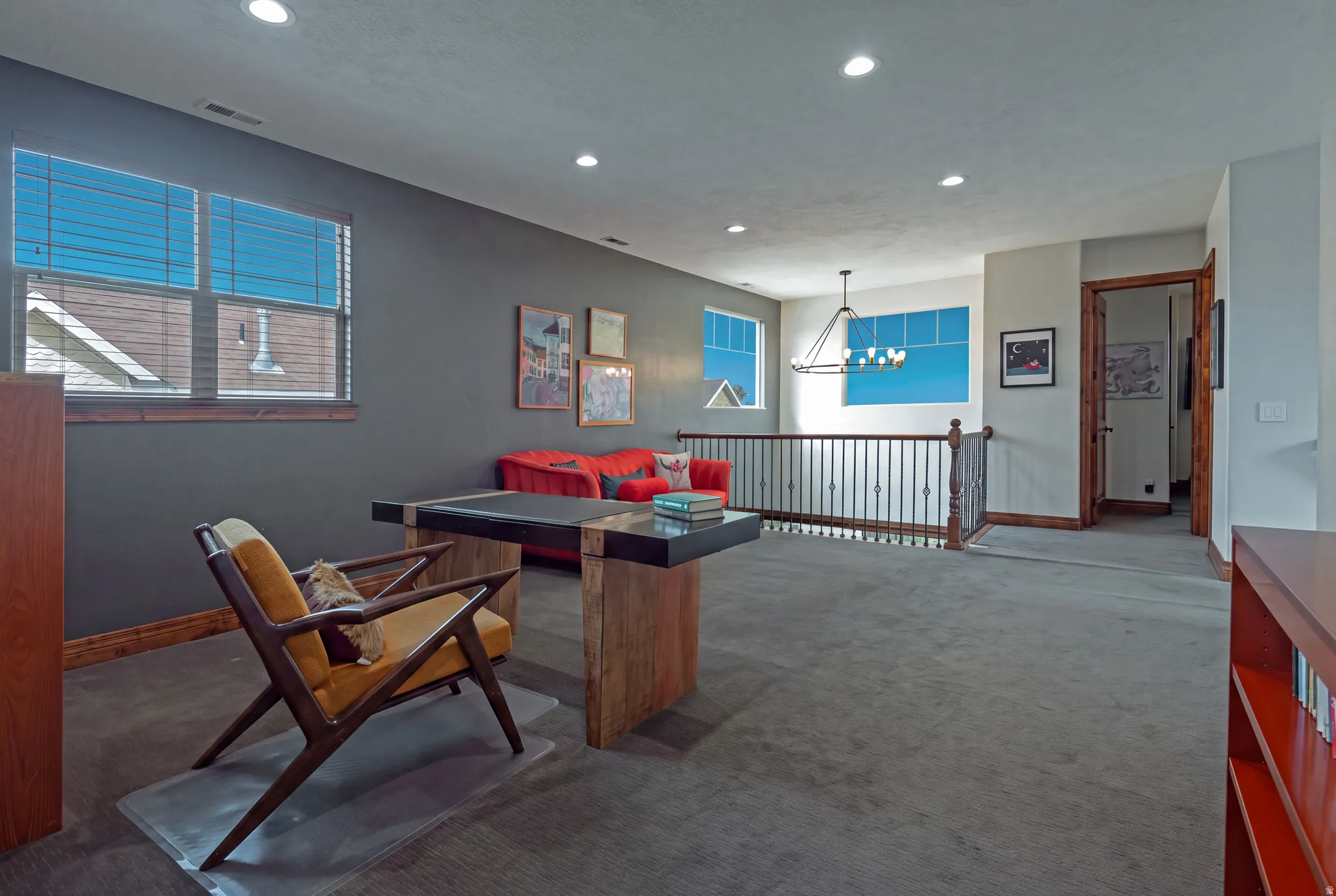 Open loft area with recessed lighting, dark gray carpeting, and a wrought iron railing
