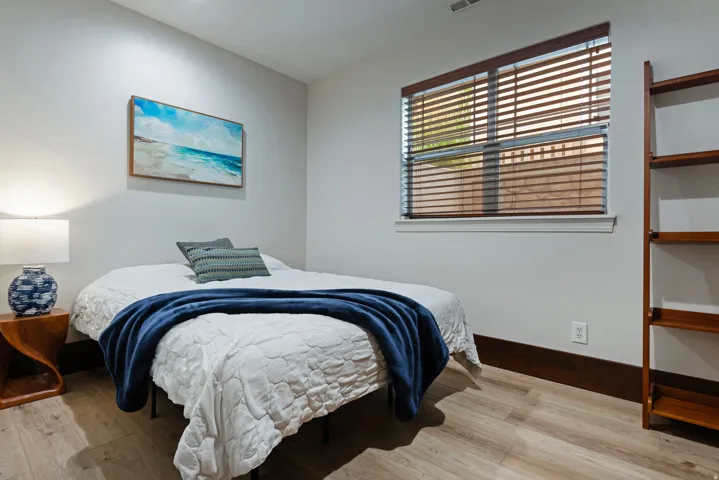 Wood-finish flooring, white walls, and a window with wood blinds