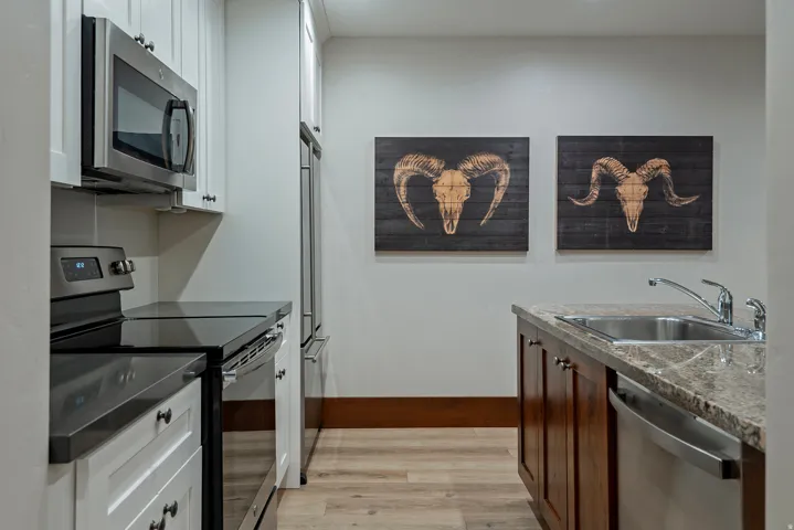 Stainless steel appliances, light wood-finish flooring, white upper cabinetry, rich wood lower cabinetry, and granite-look countertops
