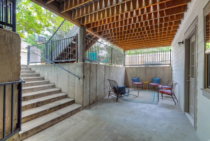 Covered concrete patio with wooden ceiling, featuring a side entry door and exterior wall sconce
