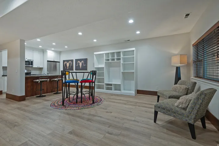 Wood-finish flooring, recessed lighting, built-in shelving, white cabinetry, and stainless steel appliances