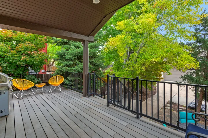 Covered outdoor deck with composite decking, black metal railings, and a solid wood beam support