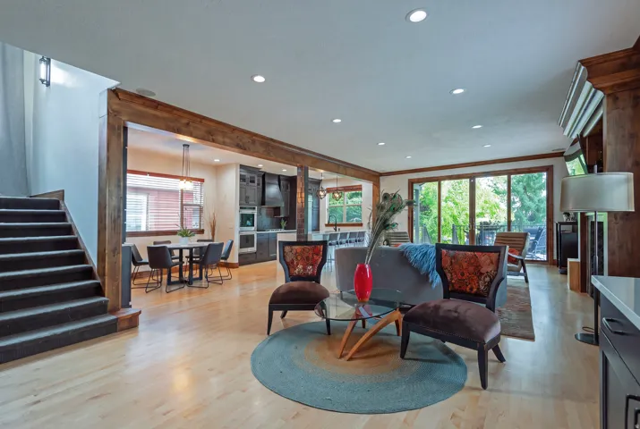 Open-concept living space featuring wood-finish flooring, recessed lighting, and exposed wood beams