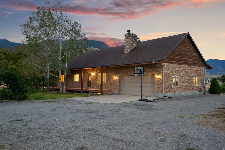 Stone and wood-sided exterior with a covered porch, attached garage, and a prominent stone chimney
