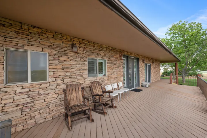 Stone veneer exterior with a covered porch featuring a composite deck, recessed lighting, and a metal railing