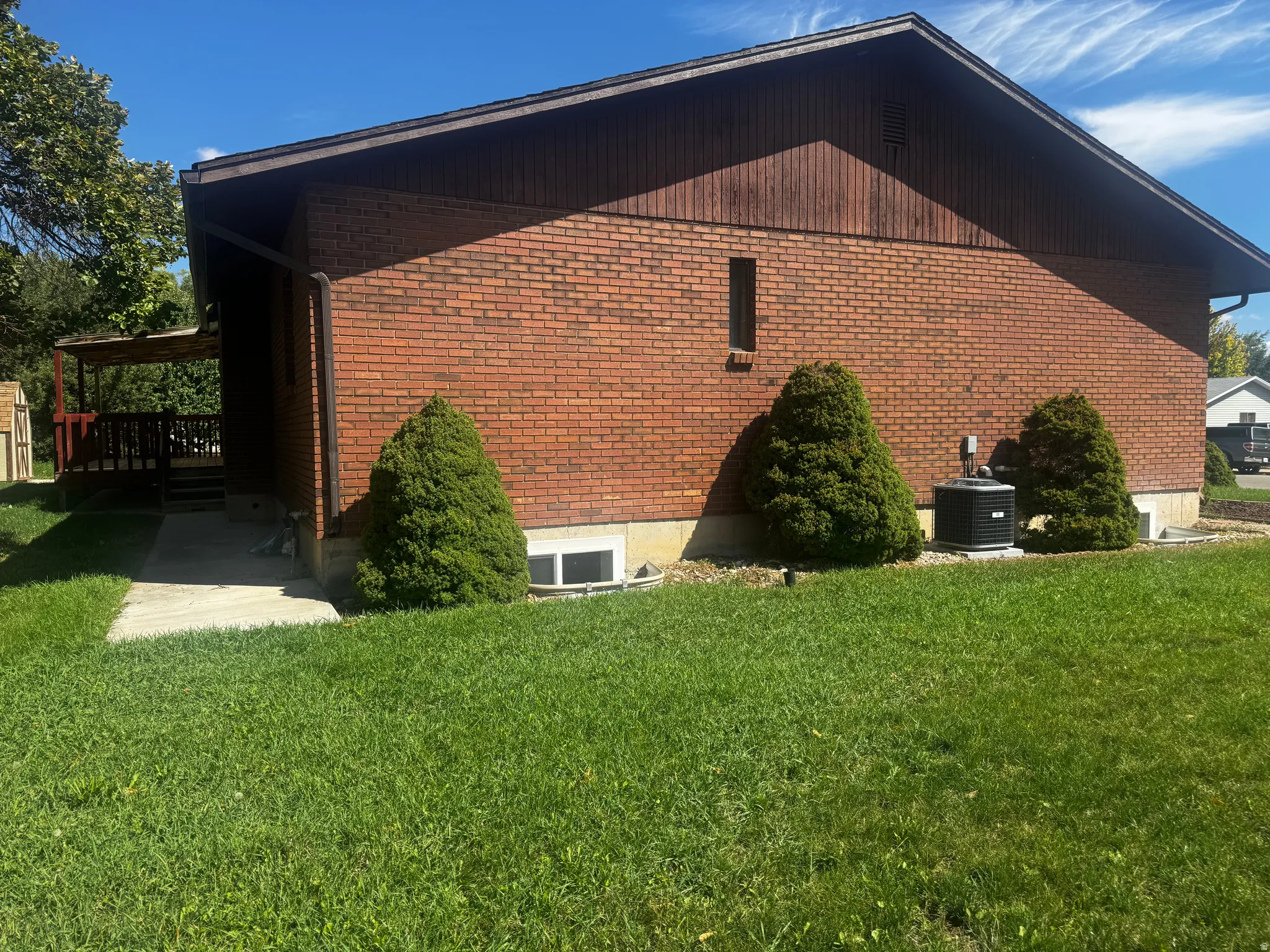 Brick exterior with wooden siding and a covered wooden deck
