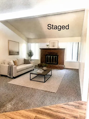 Vaulted ceiling, brick fireplace, carpeted flooring, wood-finish flooring, and multiple windows