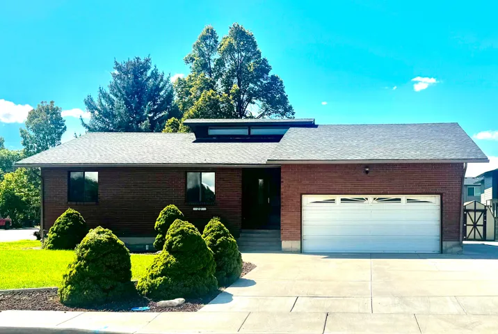 Brick exterior with a single-car garage, concrete driveway, and dormer window feature