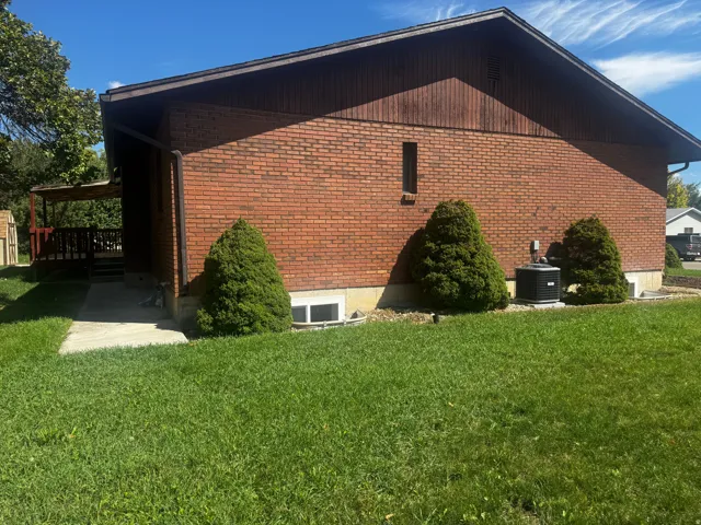 Brick exterior with wooden siding and a covered wooden deck