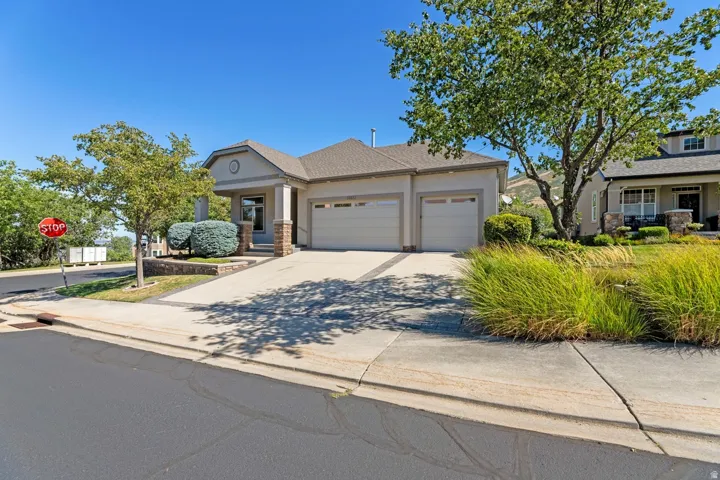 Stucco exterior with stone accents, a two-car garage, and a covered entry