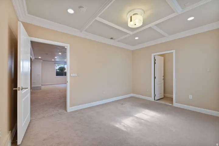 Coffered ceiling with recessed lighting and a central flush-mount fixture, neutral carpet, and white trim