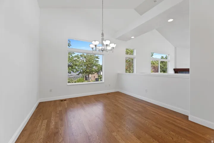 Vaulted ceilings, wood-finish flooring, recessed lighting, and multiple windows