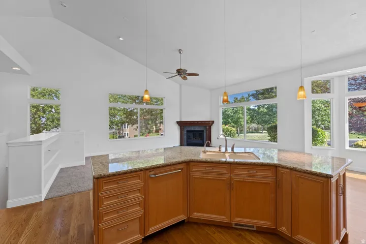 Kitchen island with stone countertops, wood-finish cabinetry, and an undermount sink