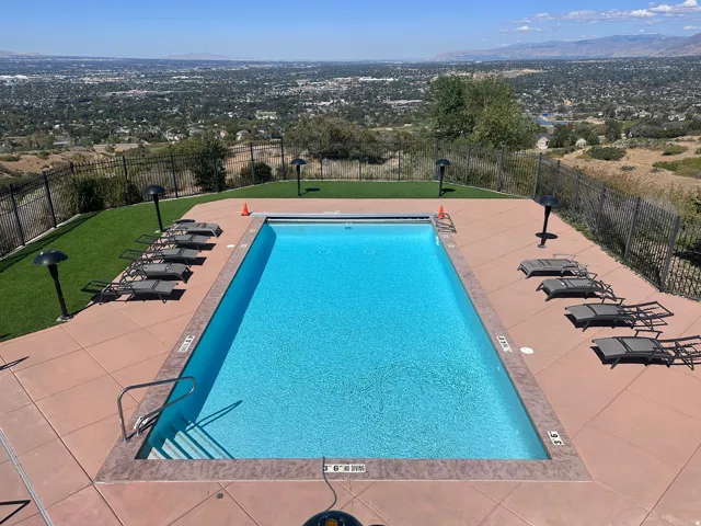 Rectangular swimming pool with integrated steps, surrounded by a paved deck and artificial turf