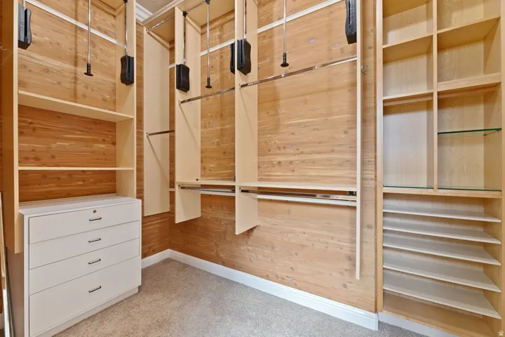 Custom closet system featuring wood-paneled walls, built-in shelving, adjustable hanging rods, and a four-drawer dresser with a lock