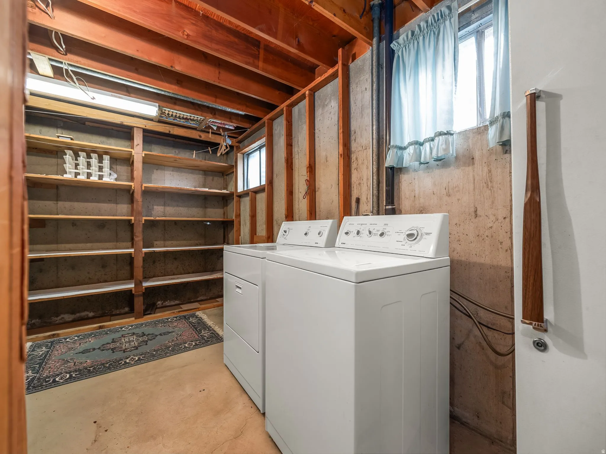 Laundry area with a washer and dryer, exposed ceiling joists, built-in shelving, and a single window