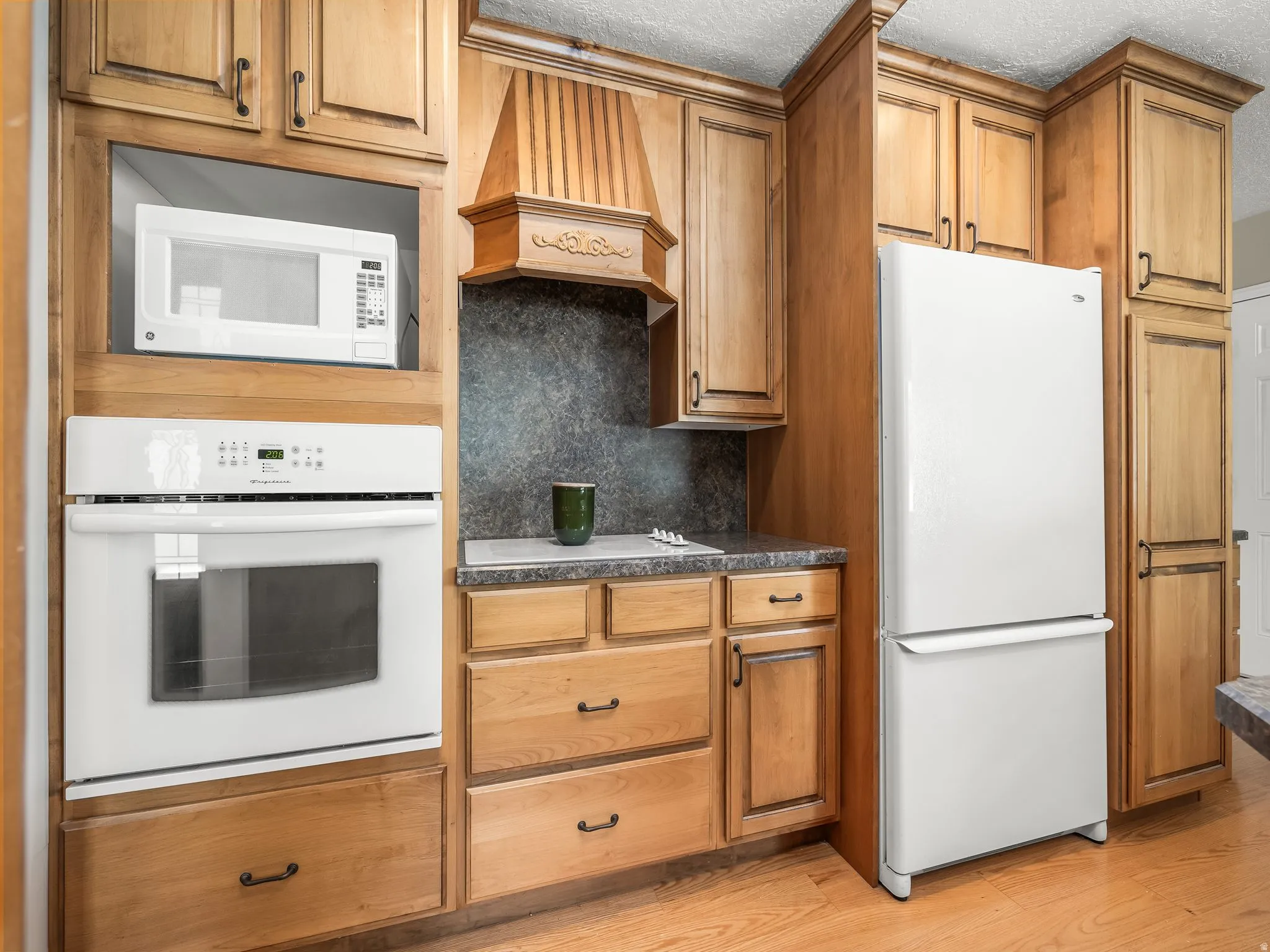 Integrated white wall oven, built-in microwave, and wood-finish cabinetry