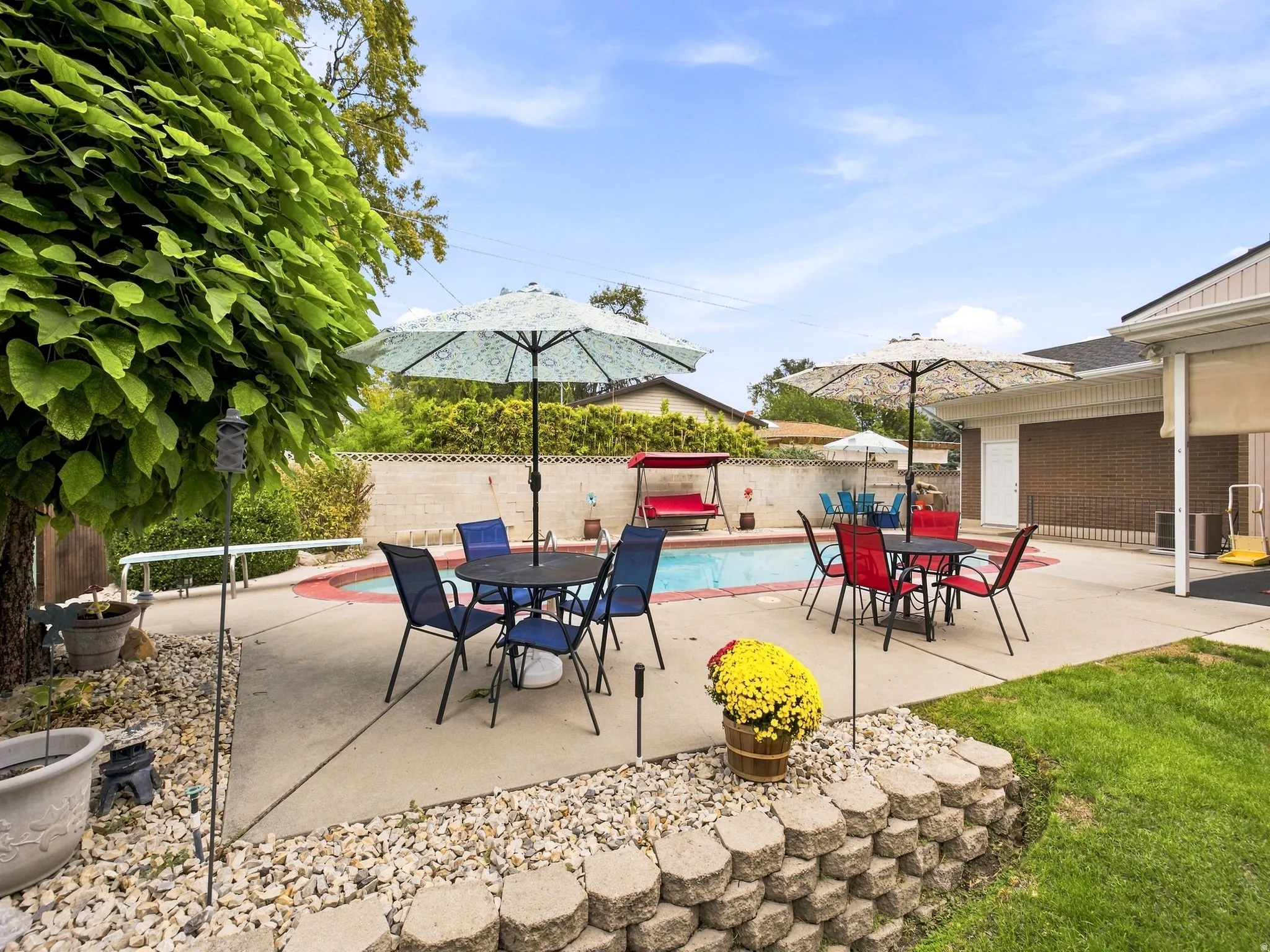 Expansive backyard featuring a built-in swimming pool, concrete patio, and a retaining wall