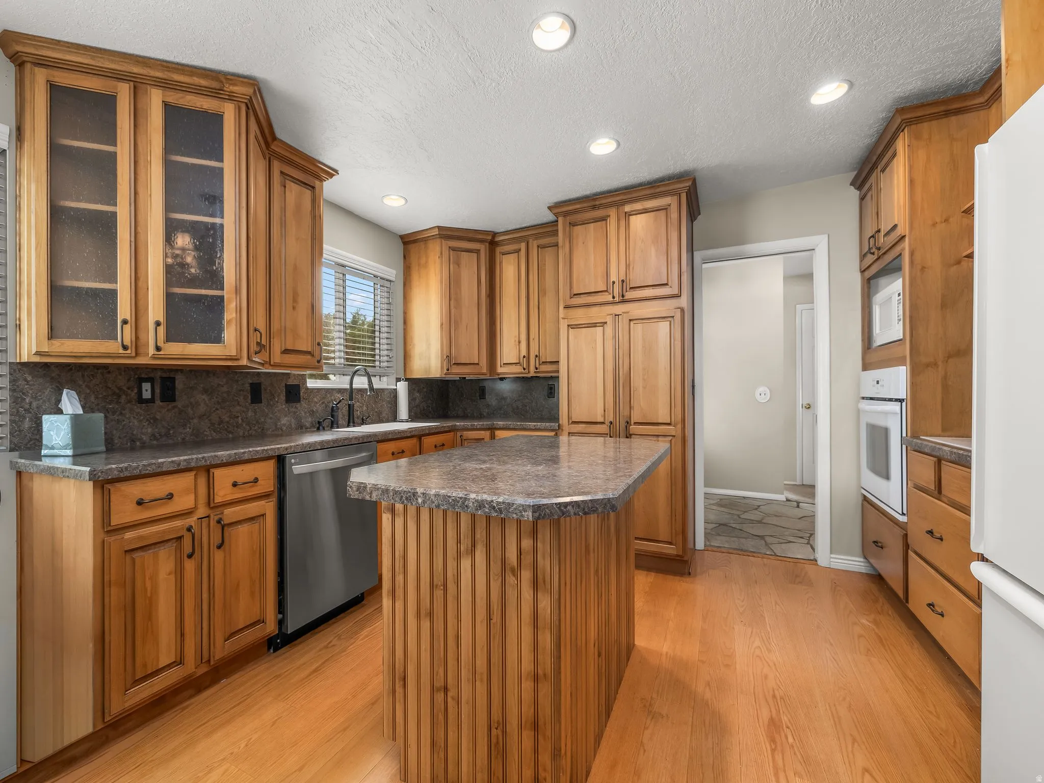 Kitchen featuring wood-finish cabinetry, built-in appliances, a central island with a countertop, and wood-finish flooring