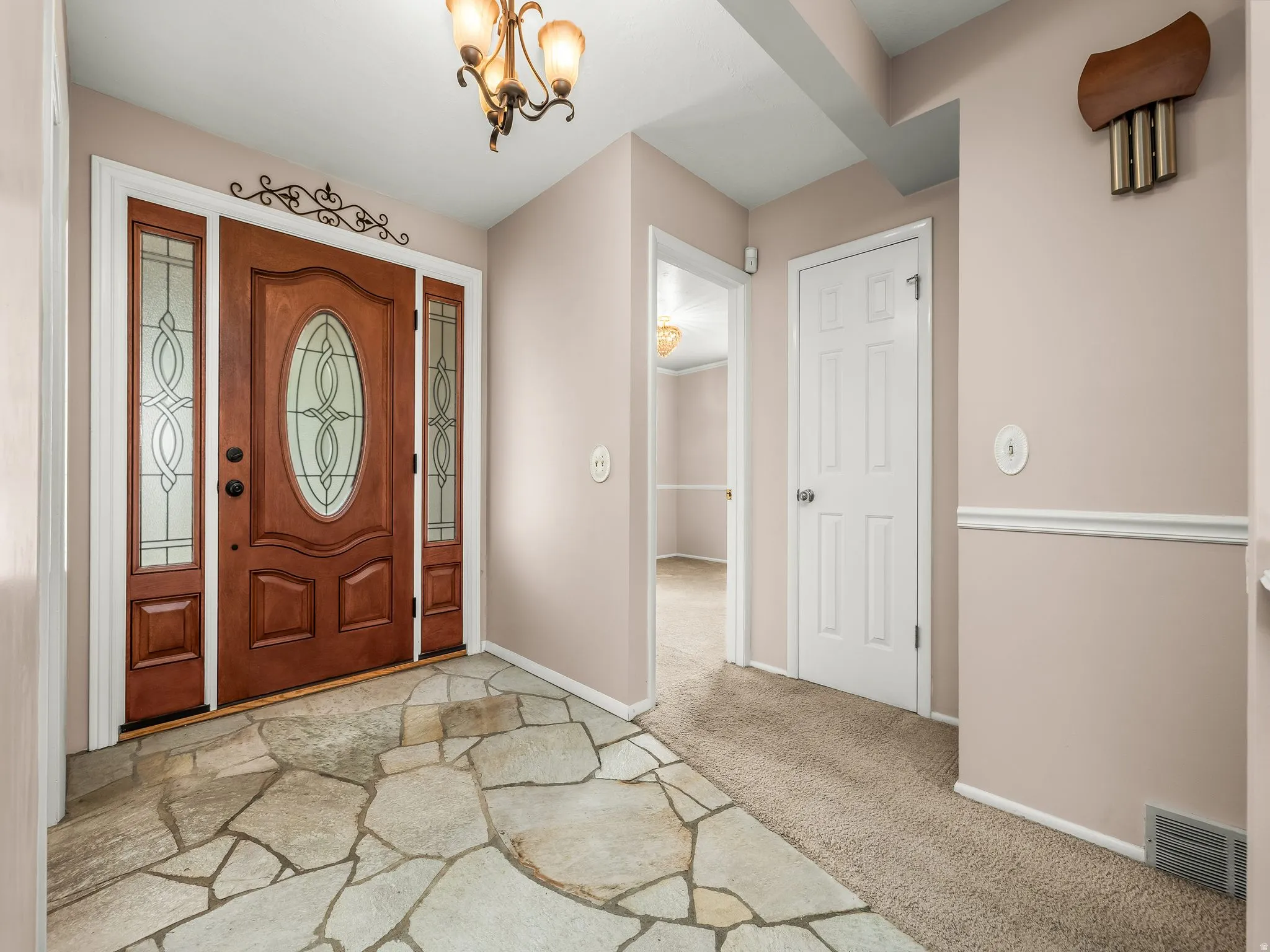 Wood-paneled entry door with decorative glass inserts and sidelights