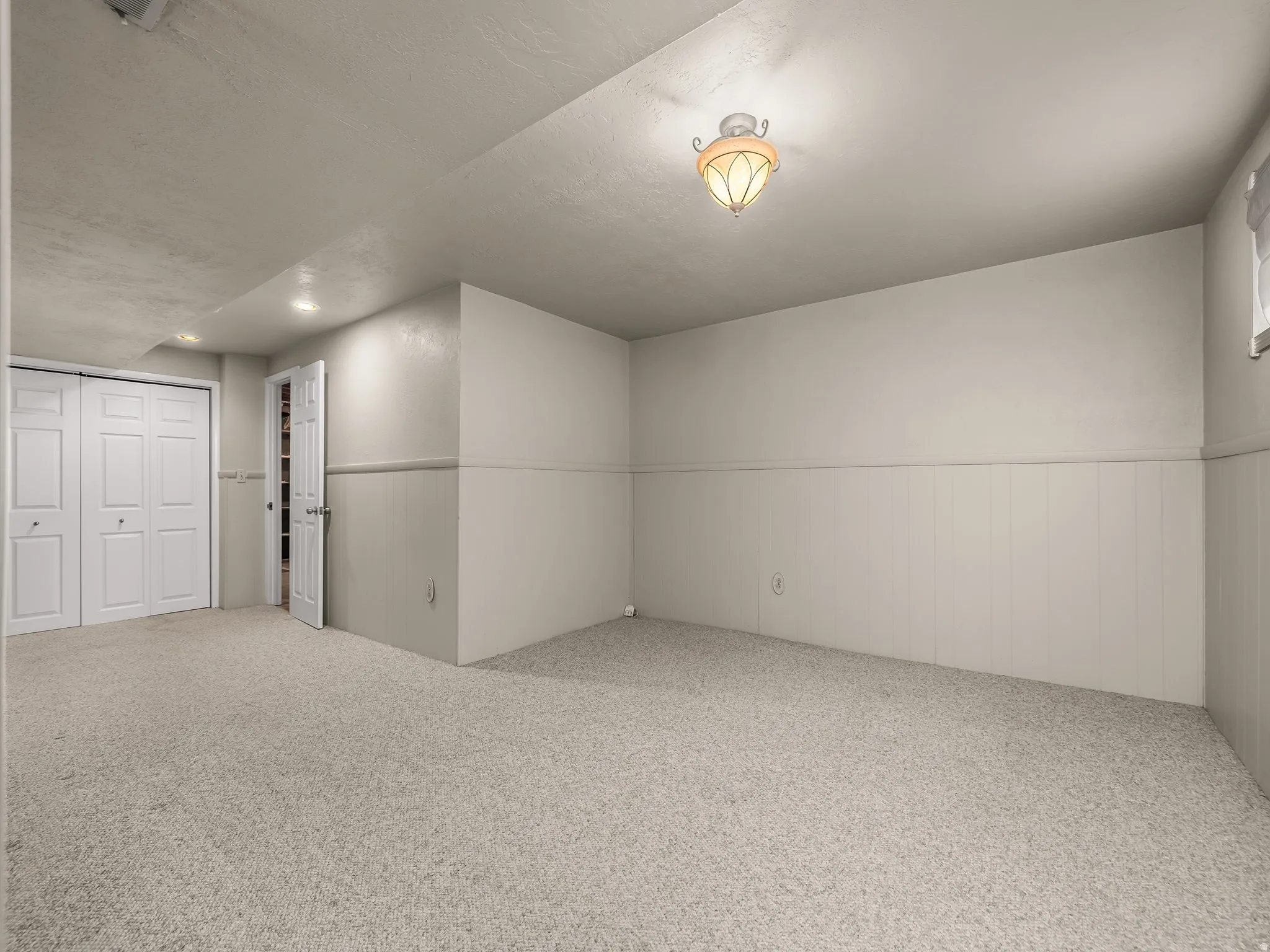 Neutral-toned carpeting, white bi-fold closet doors, recessed ceiling lighting, decorative ceiling fixture, and a white paneled wall accent